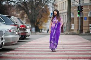 Indian hindu girl at traditional violet saree posed at street , walking at pedestrian crossing. photo