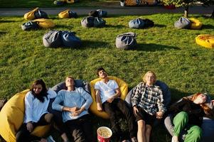 joven grupo multiétnico de personas viendo películas en poof en cine al aire libre. foto