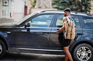 African american male athlete sport man with backpack against his black suv car before training. photo