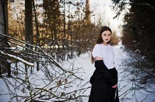Fashionable long legs brunette model in long black cloak posed outdoor at winter day. photo