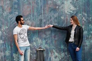 Cool pareja multirracial posando contra la pared con longboard. foto