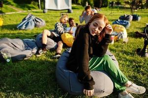 joven grupo multiétnico de personas viendo películas en poof en cine al aire libre. Cierra el retrato de una chica divertida. foto