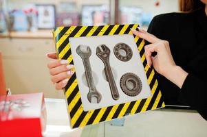 Portrait of young caucasian female woman seller hold set of mechanic tools made by chocolate. Small business of candy souvenirs shop. Present for real man. photo