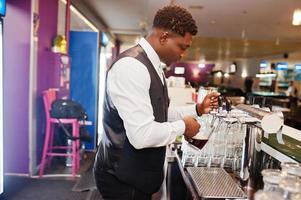 African american bartender at bar pouring from tap fresh beer into the glass in pub. photo