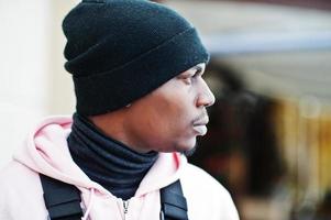 Close up head of stylish urban style african american man in pink hoodie and black hat posed. Frozen breath. photo