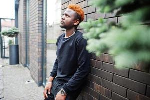 hombre de pelo rojo africano viste traje negro posando al aire libre. foto