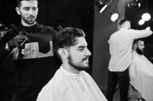 apuesto hombre barbudo en la barbería, peluquero en el trabajo. foto