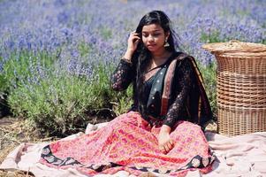 hermosa niña india usa vestido tradicional saree india en campo de lavanda púrpura. foto