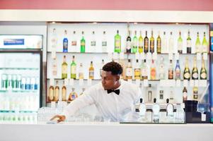 African american bartender wear on bow tie cleaning bar. photo