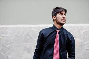 Young indian man on black shirt and tie posed outdoor. photo