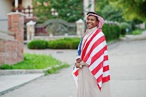 hombre árabe del medio oriente posó en la calle con la bandera de estados unidos. concepto de américa y los países árabes. foto