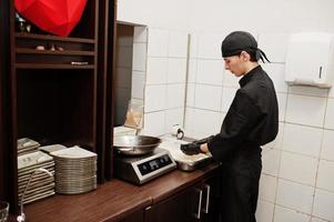 Professional chef wear in black making sushi and rolls in a restaurant kitchen of japanese traditional food. photo