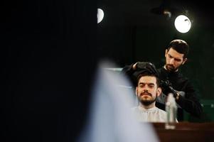 apuesto hombre barbudo en la barbería, peluquero en el trabajo. foto