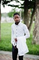 Young african american male doctor hold white coat on hand with a stethoscope posed outdoor. photo