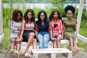 Group of five african american girls relaxing at beautiful swing. photo