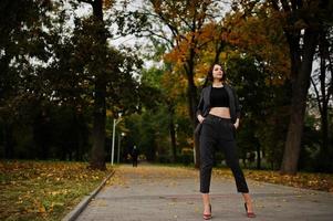 A tall leggy young beautiful and elegant model woman at formal wear posed at autumn background. photo