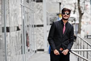 Young indian man on suit, tie and sunglasses posed outdoor. photo