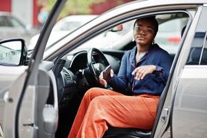 Rich business african woman sit on driver seat at silver suv car with opened door. photo