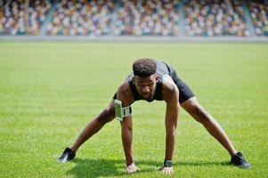 African american male athlete in sportswear doing stretching exercise at stadium. photo