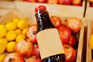 A bottle of healthy organic pomegranate juice , next to pomegranates on box. photo