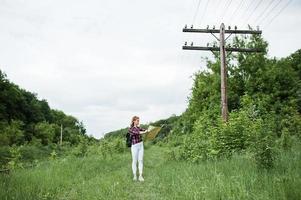 Portrait of a beautiful blond girl in tartan shirt walking with a map in the countryside. photo