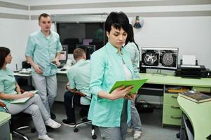 Medical theme .Portrait of female doctor with clipboard against group of doctors meeting in the mri office at diagnostic center in hospital. photo