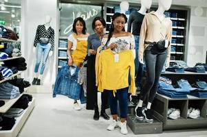 Three african woman posed near mannequins in clothes store. Shopping day at jeans sector. photo