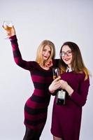 dos amigos atractivos vestidos de púrpura beben vino espumoso o champán en el estudio. foto