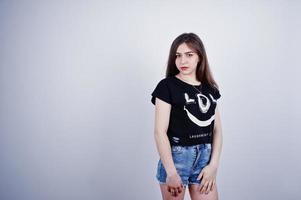 Portrait of an attractive girl in black t-shirt saying lol and denim shorts posing in the studio. photo