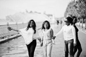 Group of four african american girls having fun against lake with fountains. photo