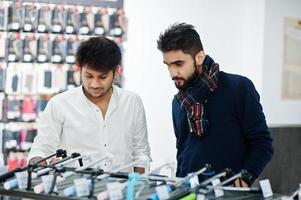 Two indians mans customer buyer at mobile phone store choose a selfie stick. South asian peoples and technologies concept. Cellphone shop. photo