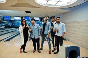 Group of five south asian peoples having rest and fun at bowling club. Holding cold soda drinks from glass bottles. photo