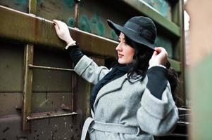 Brunette girl in gray coat with hat in railway station. photo