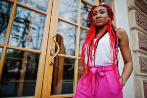 Fashionable african american girl at pink pants and red dreads posed outdoor. photo