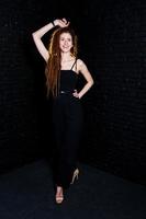 Studio shoot of girl in black with dreads on brick background. photo