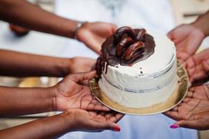 grupo de chicas afroamericanas celebrando la fiesta de cumpleaños al aire libre. manos negras con pastel. foto