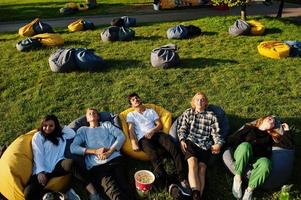 joven grupo multiétnico de personas viendo películas en poof en cine al aire libre. foto