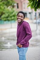 Young african american man in violet jumper posed against fountain alley. photo