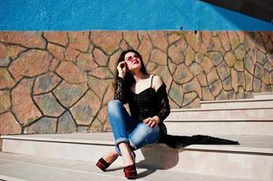 Portrait of brunette girl in pink glasses wear on black posed outdoor on sunny day. photo