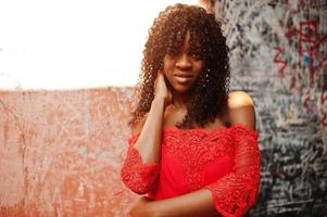 elegante mujer rizada afro francia de moda posó en el día de otoño con vestido rojo. modelo de mujer africana negra. foto