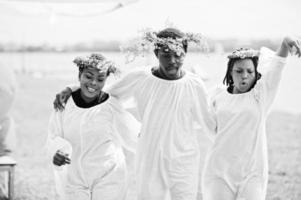 Three african american friends on white cloaks and wreath having fun together. photo