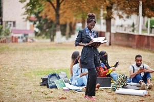 grupo de cinco estudiantes universitarios africanos que pasan tiempo juntos en el campus en el patio de la universidad. amigos negros afro estudiando. tema de la educación foto