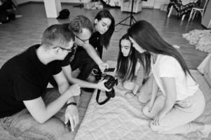 el equipo de fotógrafos que muestra imágenes en la pantalla de la cámara para las niñas modelos gemelas en el estudio. fotógrafo profesional en el trabajo. foto