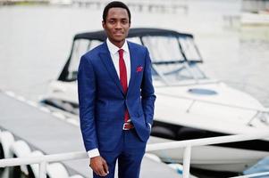 African american happy successful man at suit against yacht. Rich black business man. photo