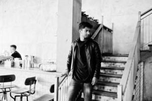 Casual and stylish young asian man wear on leather jacket standing on stairs at cafe. photo