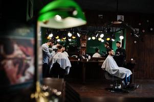 apuesto hombre barbudo en la barbería, peluquero en el trabajo. foto