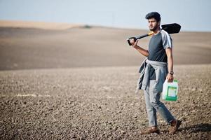 South asian agronomist farmer with shovel inspecting black soil. Agriculture production concept. photo