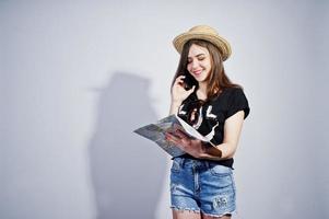 Girl tourist with map, wear in lol shirt, shorts and hat speaking on mobile phone isolated on white. photo