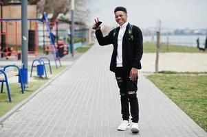 joven africano milenario caminando en la ciudad. hombre negro feliz con mochila de marihuana. concepto de generación z. foto