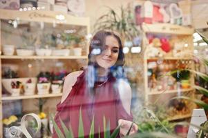 Brunette girl in red buy flowers at flower store. photo